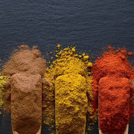 Ground spices in assorted colours on wooden scoops